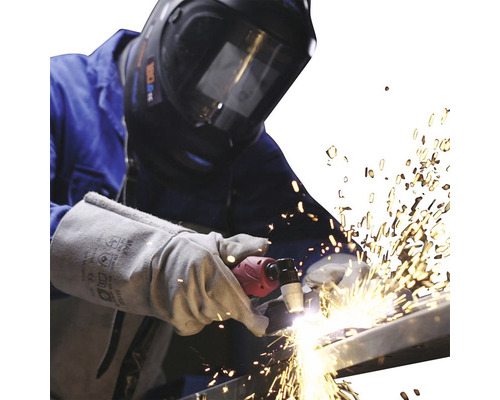 Svářeč se svařovací helmou a rukavicemi plazmově řeže kov