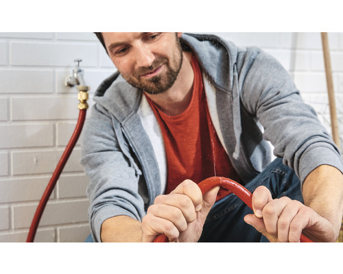 Muž kontroluje netěsný systém vodní hadice v interiéru