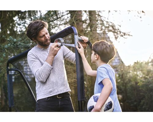 Otec a syn opravují fotbalovou branku lepicí páskou na zahradě.