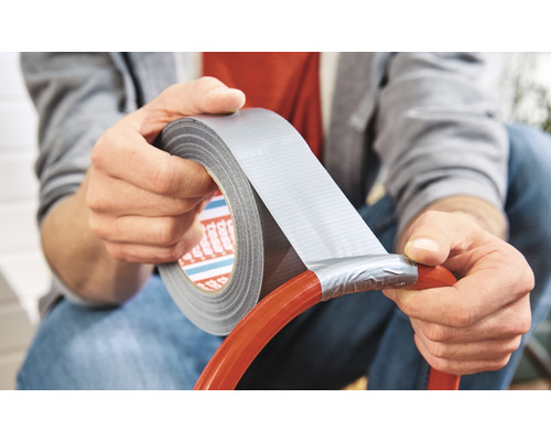 Osoba používá lepicí pásku k opravě trubky.