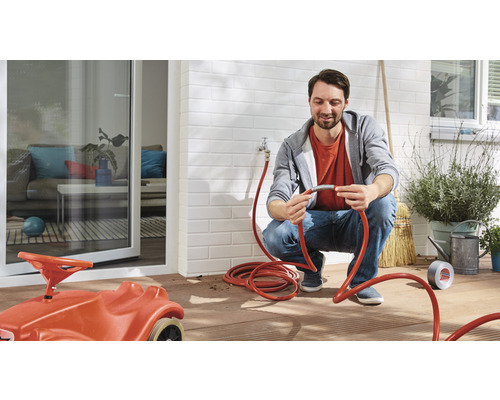 Muž opravuje zahradní hadici na terase s hračkou