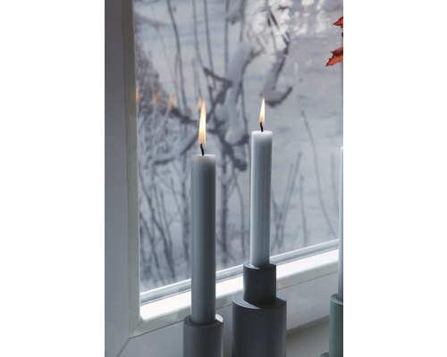 Dekorativní stolní svíčky ve svícnech na okenním parapetu