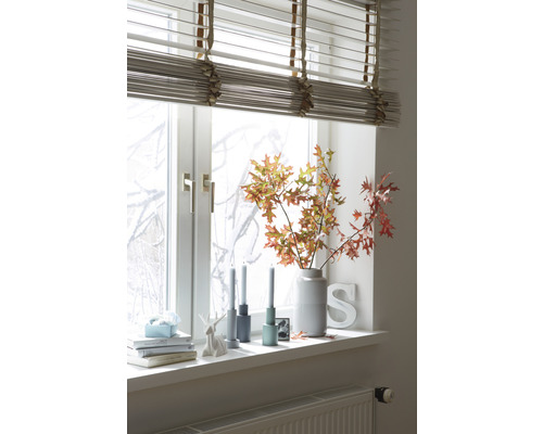 Dekorace okna se žaluziemi, váza s větvemi, svíčky a dekorativní předměty na parapetu