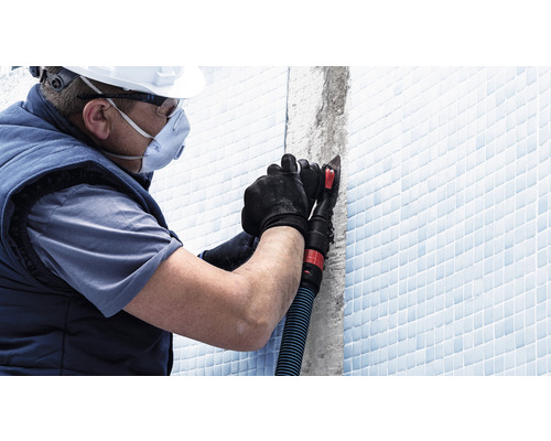 Řemeslník s osobními ochrannými prostředky při zpracování spár dlaždic