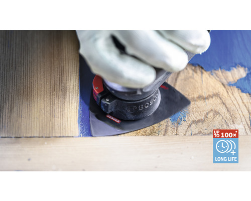 Muž v rukavicích používá brusný nástroj na kusu dřeva k odstranění barvy. Logo Bosch.