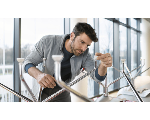 Muž montuje kovový věšák na oblečení.