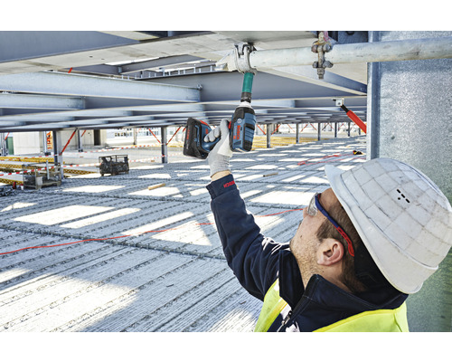 Stavební dělník používá akumulátorový rázový utahovák na staveništi.