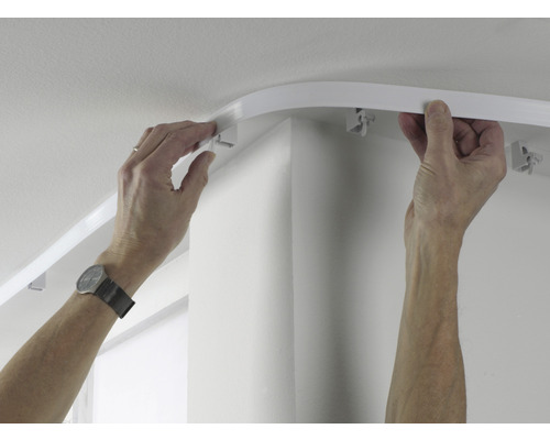 Osoba montuje záclonovou lištu na strop