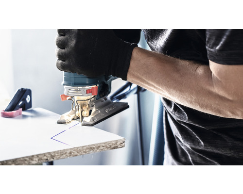 Přímočará pila řeže linku do obrobku. Uživatel má na sobě rukavice.
