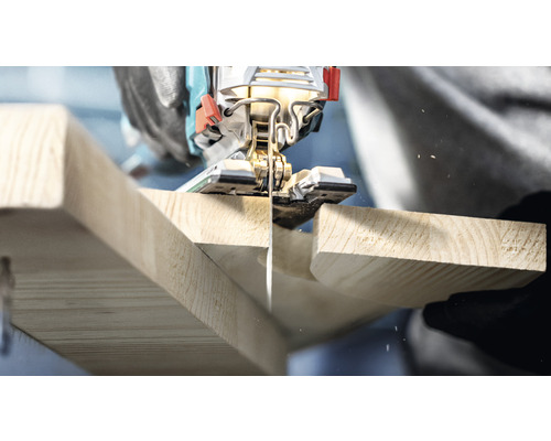 Detailní záběr na přímočarou pilu řezající dřevěnou desku