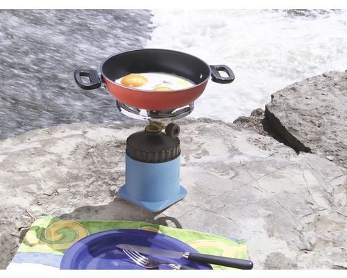 Kempingový vařič s pánví a smaženými vejci na skále vedle vodopádu