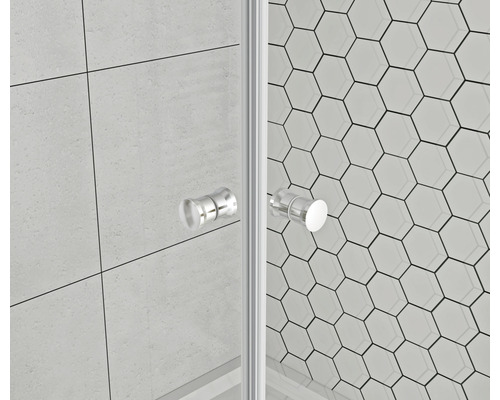 Detailní záběr sprchového koutu se skleněnými stěnami a madly na pozadí šestiúhelníkových dlaždic