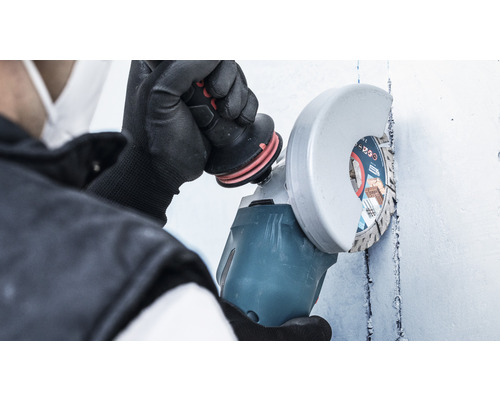 Osoba používá úhlovou brusku na zdi.