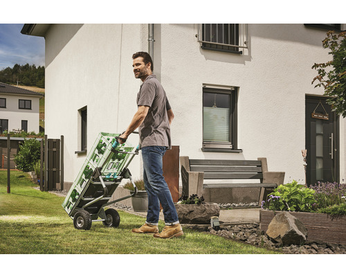 Muž přepravuje přepravky s nápoji na rudlu na zahradě.