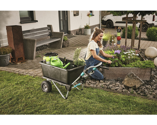 Žena pracuje na zahradě s kolečkem a truhlíkem