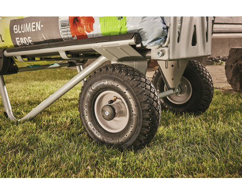 Detailní pohled na transportní vozík s květinovou zeminou na trávníku.