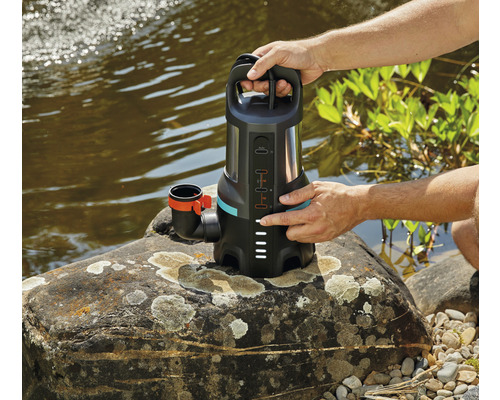 Ponorné akumulátorové čerpadlo Gardena s ovládacím prvkem na kameni u jezera