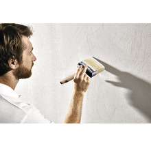 Muž maluje stěnu štětkou.