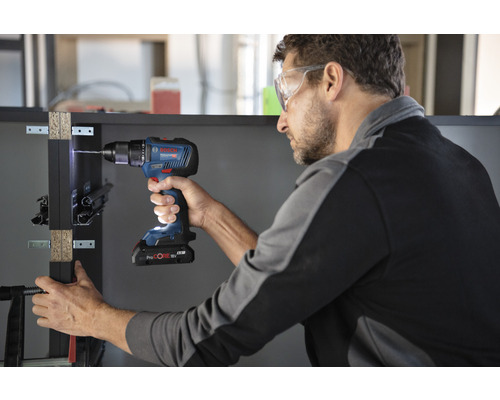 Muž vrtá obrobek pomocí akumulátorového šroubováku Bosch.