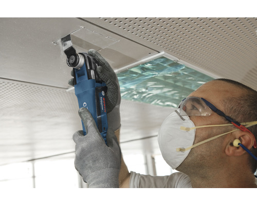 Řemeslník pracuje s multifunkčním nástrojem na stropní desce