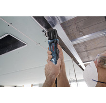 Řemeslník používá multifunkční nástroj Bosch Professional k úpravě stropního panelu.