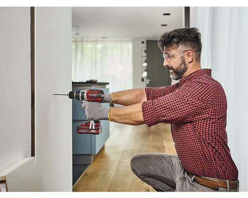 Muž vrtá vrtačkou díru do zdi.