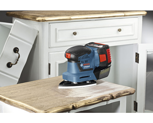 Akumulátorová excentrická bruska Bosch Professional na komodě