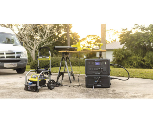 Vysokotlaký čistič Ryobi, fukar na listí a akumulátorový vrtací šroubovák spolu s napájecí stanicí Bluetti na příjezdové cestě.