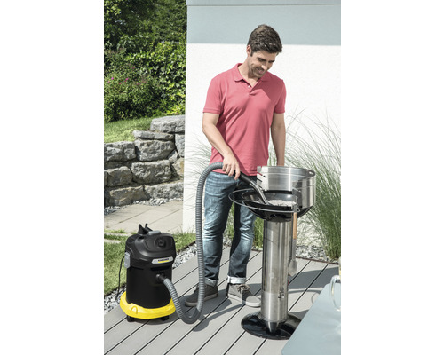 Muž čistí gril na dřevěné uhlí s vysavačem popela venku