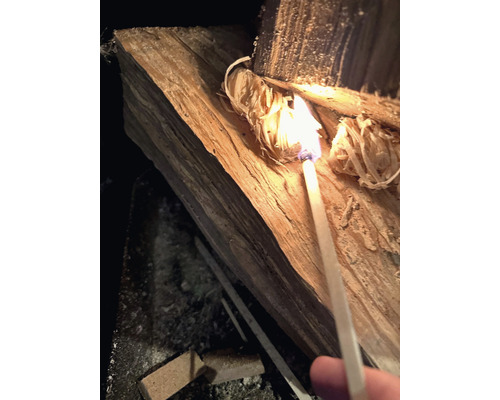 Kousek dřeva se zapaluje zápalkou.