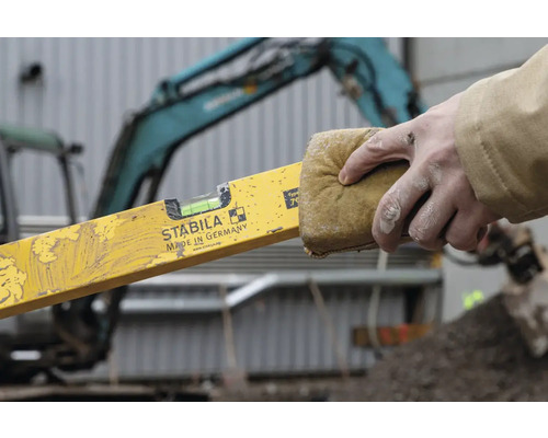 Osoba čistí vodováhu houbou před použitím.