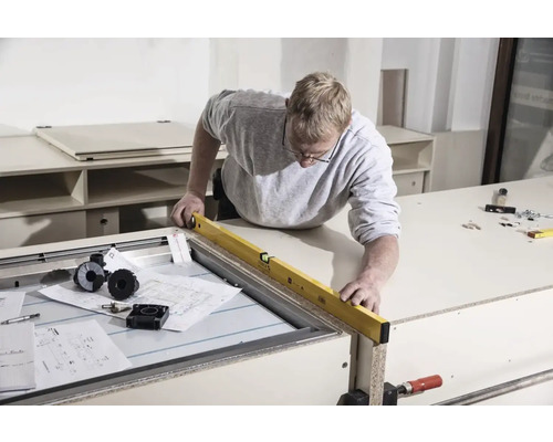 Řemeslník kontroluje pracovní stůl pomocí vodováhy.