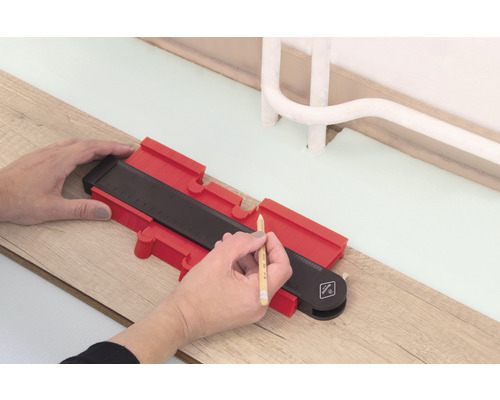 Osoba používá obrysovou šablonu k orýsování na dřevěné podlaze