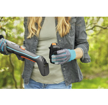 Žena vkládá baterii do akumulátorových nůžek na trávu Gardena