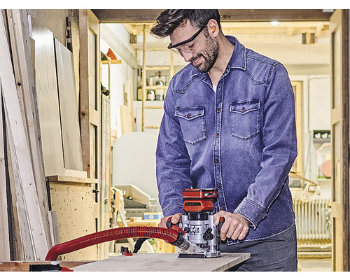 Muž v dílně používá horní frézku na práci se dřevem.