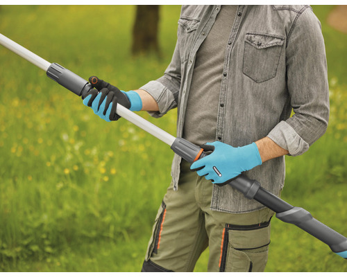 Osoba v zahradních rukavicích drží venku teleskopické prodloužení násady.
