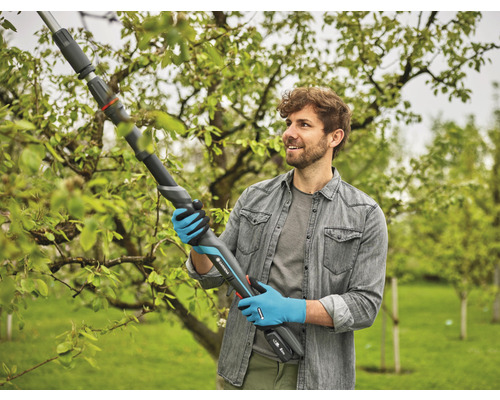 Muž používá akumulátorové nůžky na větve Gardena pro prořezávání větví na zahradě.