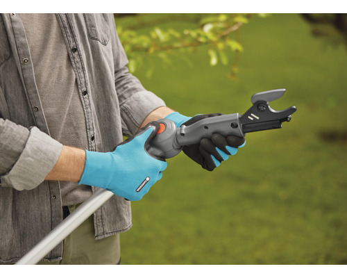 Osoba obsluhuje nůžky na větve na tyči se zahradními rukavicemi.