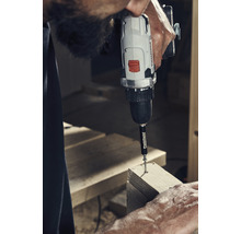 Muž šroubuje šroub pomocí akumulátorového šroubováku do dřeva