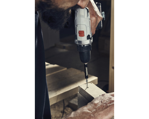 Muž šroubuje šroub pomocí akumulátorového šroubováku do dřeva