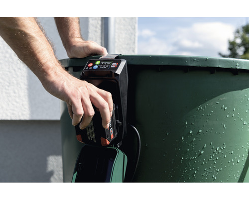 Muž vkládá baterii do čerpadla dešťové nádrže.