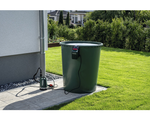 Zahradní scéna s nádrží na dešťovou vodu, stěnou domu, okapovou trubkou a ponorným čerpadlem s logem Metabo