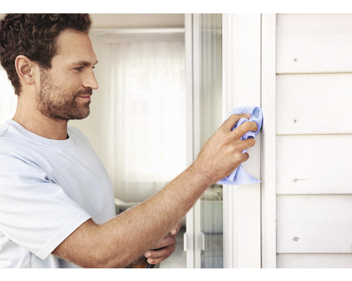 Muž čistí rám okna hadříkem