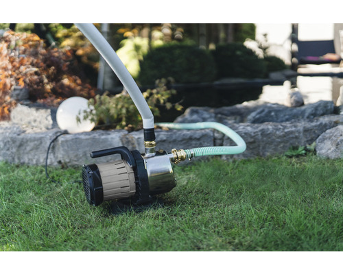 Zahrada se zahradním čerpadlem a zavlažovací hadicí na trávníku