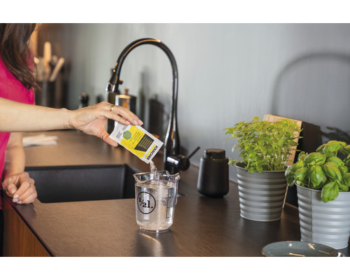 Žena vlévá čisticí prostředek Kärcher do odměrky s vodou.