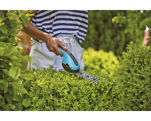 Akumulátorové nůžky na trávu Gardena používané k tvarování keřů