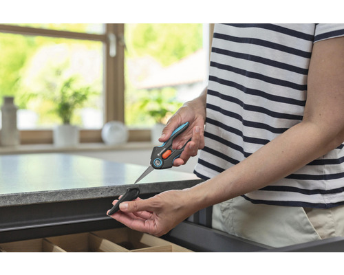 Osoba drží nůžky na rostliny Gardena s ochranným krytem nad zásuvkou.