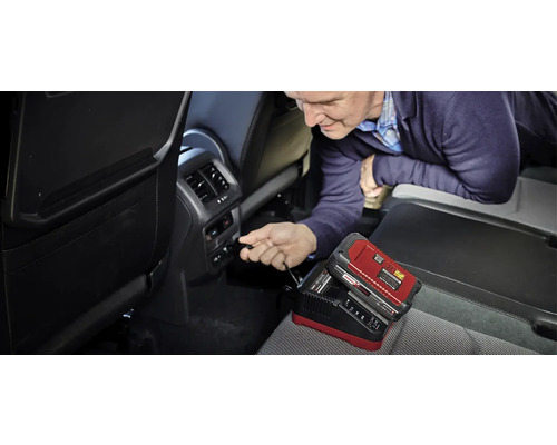 Muž připojuje nabíječku autobaterií v autě