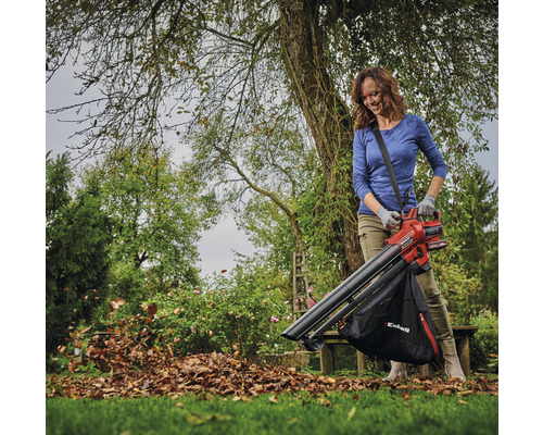 Žena používá vysavač listí na zahradě k odstranění listí.