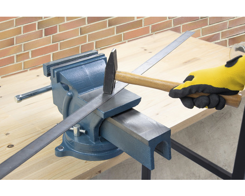 Pracovní stůl se svěrákem, kladivem a kusem kovu